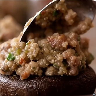 A platter of golden-brown sausage stuffed baby bella mushrooms garnished with fresh parsley and Parmesan cheese.