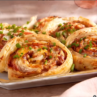A close-up of tightly rolled tortilla pinwheels sliced into bite-sized rounds, showing layers of deli ham, cheddar cheese, and herbed cream cheese