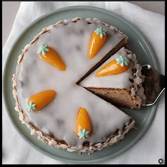 Whole Swiss Aargau carrot cake with white lemon glaze, toasted almonds on the sides, and marzipan carrots on top