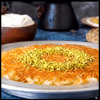 Sizzling golden-brown crispy Künefe Turkish sweet cheese pastry garnished with finely ground pistachios