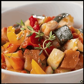An elegant sliced vegetable ratatouille with layers of zucchini, eggplant, and squash in a rich tomato base